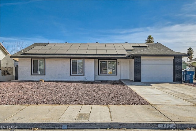 ranch-style home featuring solar panels and a garage