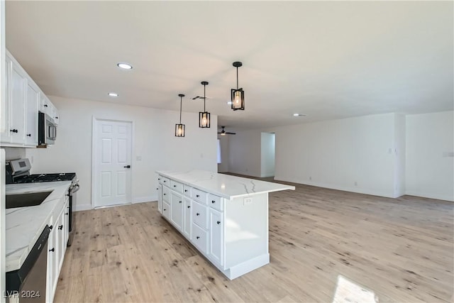 kitchen featuring a kitchen island, pendant lighting, light wood-type flooring, white cabinets, and appliances with stainless steel finishes