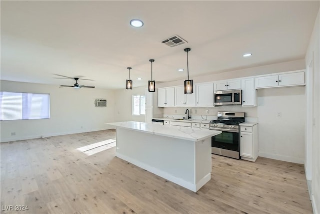 kitchen with stainless steel appliances, pendant lighting, a center island, light hardwood / wood-style floors, and white cabinetry