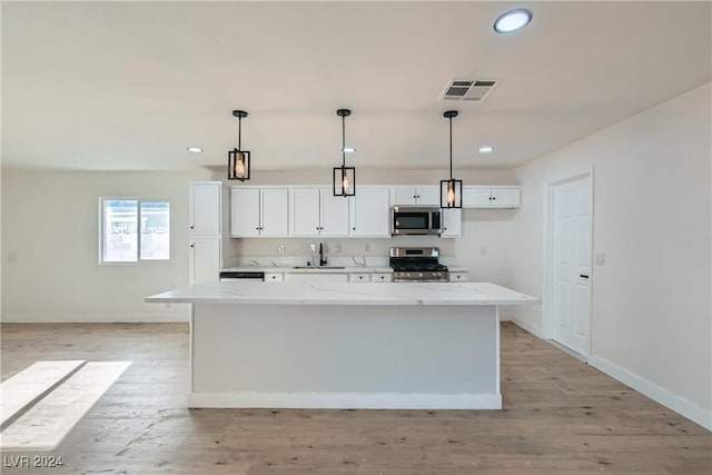 kitchen with pendant lighting, a center island, white cabinets, and stainless steel appliances