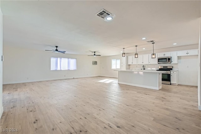 kitchen featuring a healthy amount of sunlight, white cabinets, stainless steel appliances, and decorative light fixtures