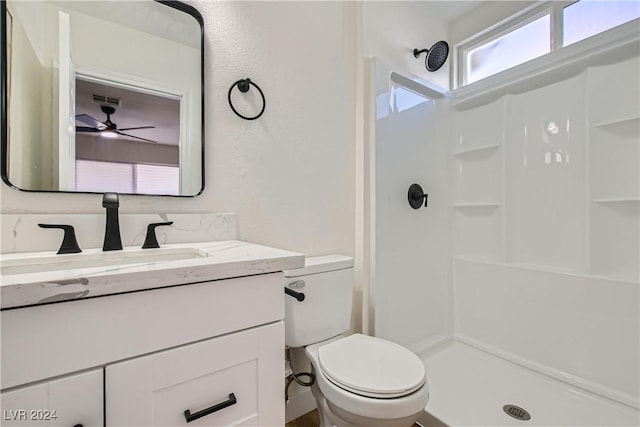 bathroom featuring vanity, toilet, walk in shower, and ceiling fan