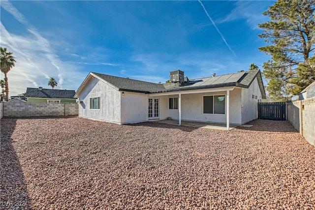 back of property featuring french doors, a patio, and solar panels