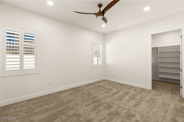 unfurnished bedroom featuring ceiling fan, a closet, carpet, and a spacious closet