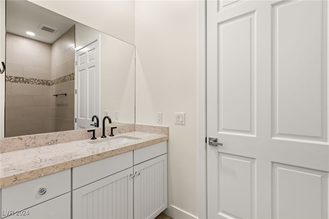 bathroom featuring a tile shower and vanity