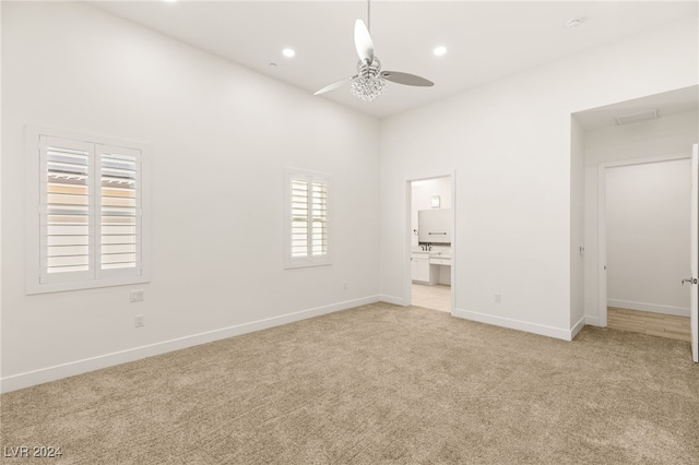 unfurnished bedroom featuring ceiling fan, light carpet, and connected bathroom