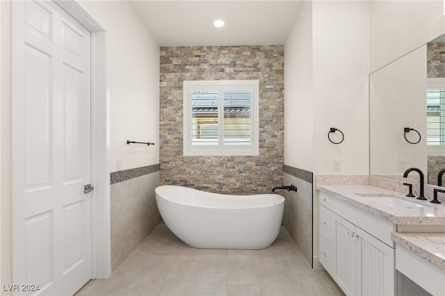 bathroom featuring a bathing tub, vanity, tile walls, and tile patterned flooring