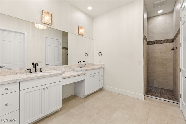 bathroom featuring tile patterned flooring, a tile shower, and vanity