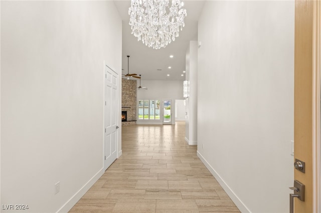 hall with a chandelier, a towering ceiling, and light hardwood / wood-style floors