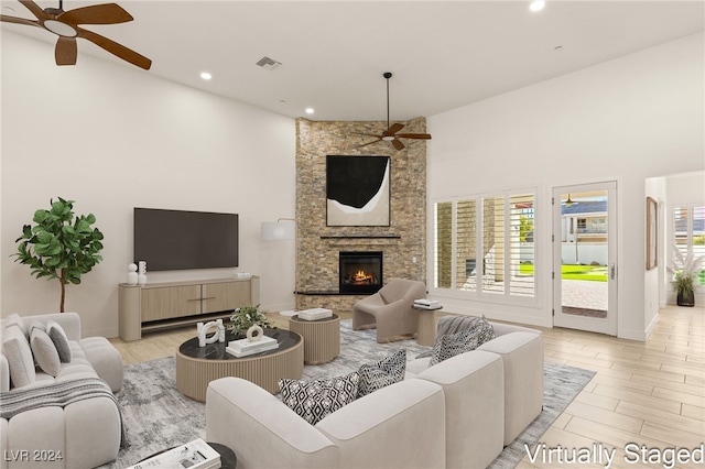 living room featuring a fireplace, a towering ceiling, and ceiling fan