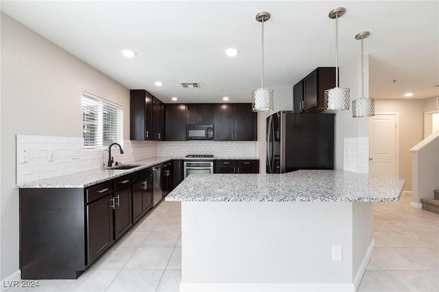 kitchen featuring sink, appliances with stainless steel finishes, decorative light fixtures, a kitchen island, and dark brown cabinetry