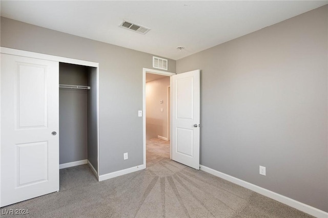 unfurnished bedroom featuring light carpet and a closet