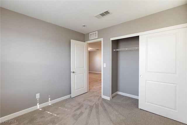 unfurnished bedroom with light colored carpet and a closet