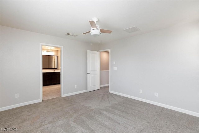 unfurnished bedroom with ensuite bathroom, ceiling fan, and light carpet