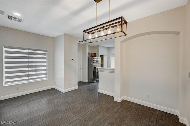 unfurnished dining area featuring dark hardwood / wood-style flooring and a notable chandelier