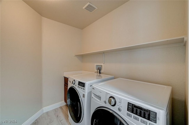 clothes washing area featuring independent washer and dryer and light hardwood / wood-style floors