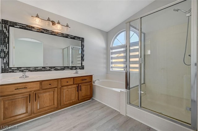 bathroom featuring shower with separate bathtub, vanity, vaulted ceiling, and hardwood / wood-style flooring