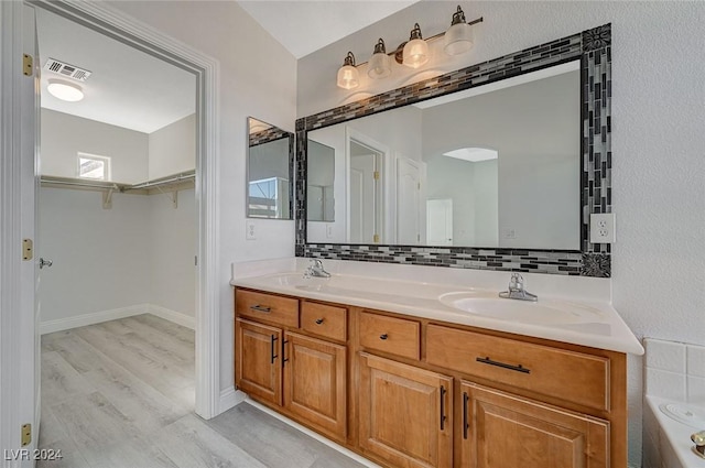 bathroom with tasteful backsplash, a tub, vanity, and hardwood / wood-style flooring