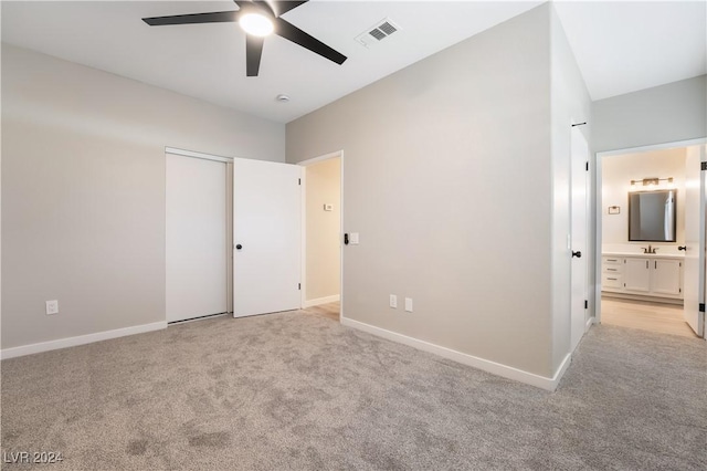 unfurnished bedroom featuring ceiling fan, a closet, light carpet, and ensuite bath