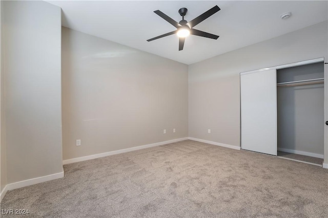 unfurnished bedroom featuring ceiling fan, a closet, and light colored carpet