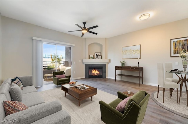 living room featuring a fireplace, ceiling fan, and light hardwood / wood-style flooring