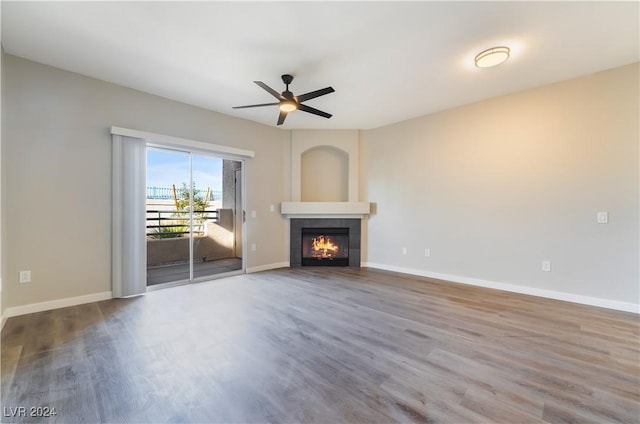 unfurnished living room featuring a tile fireplace, hardwood / wood-style flooring, and ceiling fan