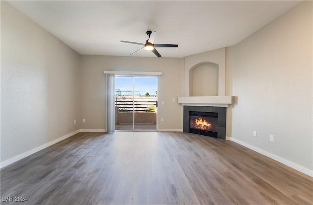 unfurnished living room featuring hardwood / wood-style flooring, ceiling fan, and a tiled fireplace