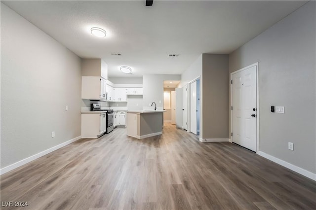 kitchen with light wood-type flooring, a center island, stainless steel stove, and white cabinetry