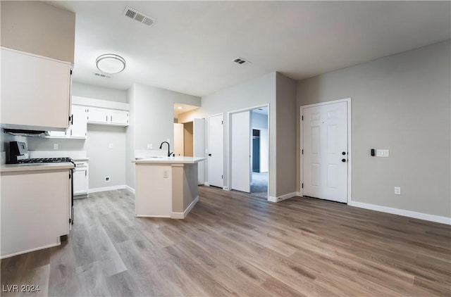 kitchen with sink, white cabinetry, white gas range oven, and light hardwood / wood-style flooring