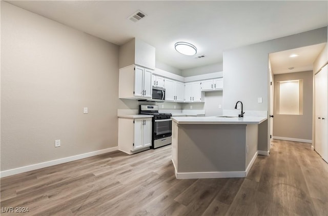 kitchen with white cabinets, stainless steel appliances, light hardwood / wood-style floors, and sink