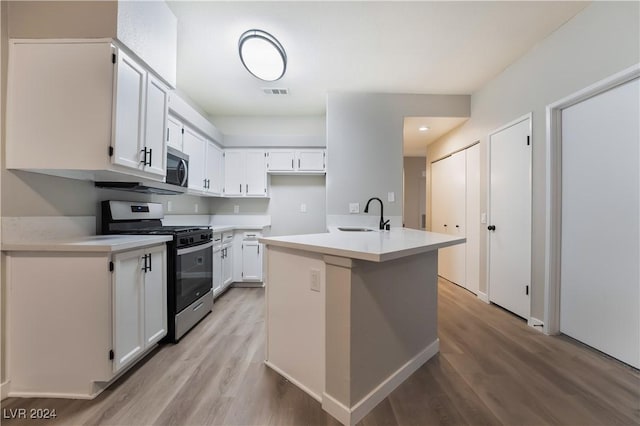 kitchen featuring appliances with stainless steel finishes, light wood-type flooring, a kitchen island with sink, sink, and white cabinetry