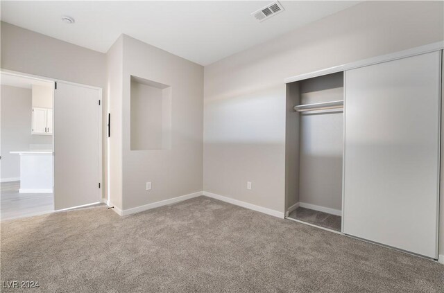 unfurnished bedroom with light carpet and a closet