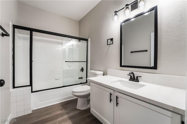 full bathroom featuring toilet, vanity, enclosed tub / shower combo, and hardwood / wood-style flooring