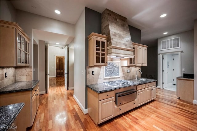 kitchen with sink, light wood-type flooring, light brown cabinetry, tasteful backsplash, and custom range hood