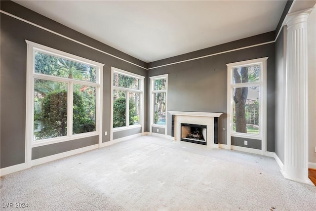 unfurnished living room featuring carpet and decorative columns