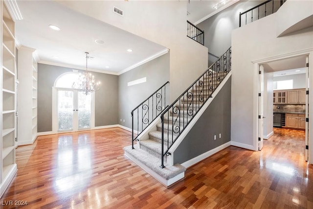 entryway with french doors, beverage cooler, crown molding, a chandelier, and hardwood / wood-style flooring