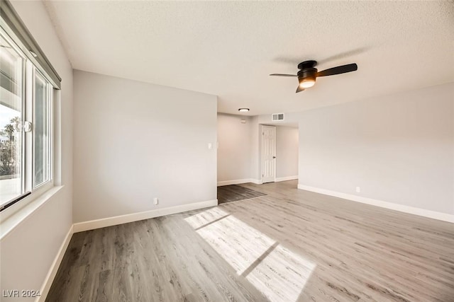 empty room with ceiling fan, a textured ceiling, and hardwood / wood-style flooring