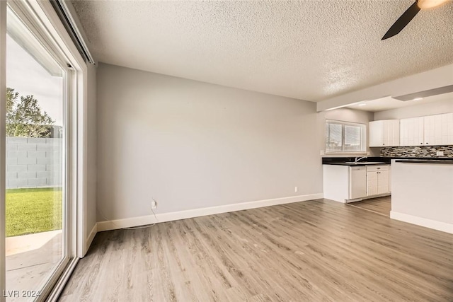 kitchen featuring decorative backsplash, wood-type flooring, white cabinetry, and a wealth of natural light