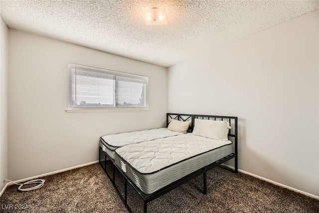 bedroom with a textured ceiling and dark colored carpet