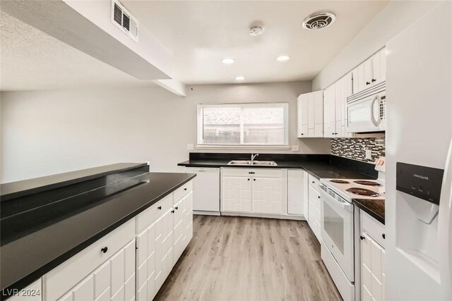 kitchen with tasteful backsplash, white appliances, sink, white cabinets, and light hardwood / wood-style floors