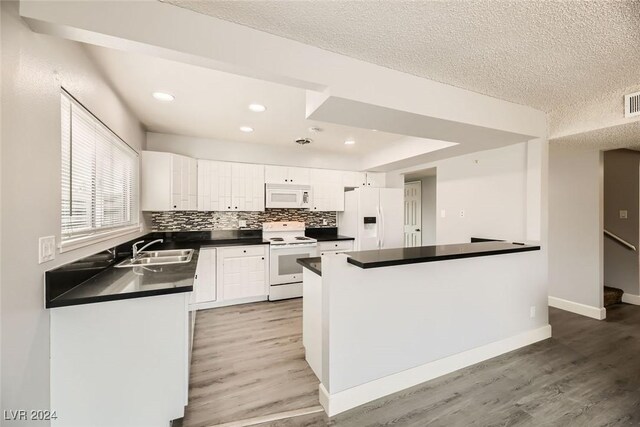 kitchen featuring white appliances, white cabinets, sink, light wood-type flooring, and a textured ceiling