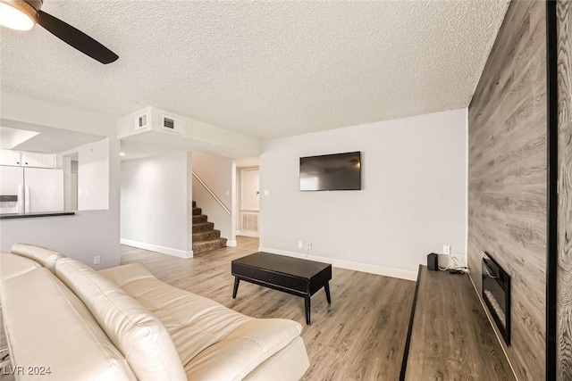 living room featuring ceiling fan, wood-type flooring, and a textured ceiling