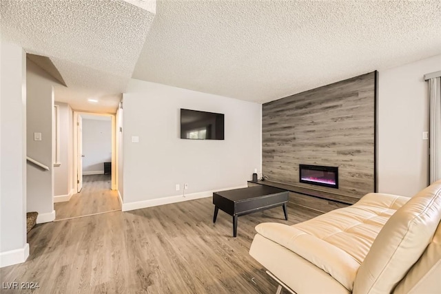 living room featuring a large fireplace, a textured ceiling, and light hardwood / wood-style flooring