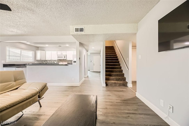 living room with a textured ceiling and light wood-type flooring