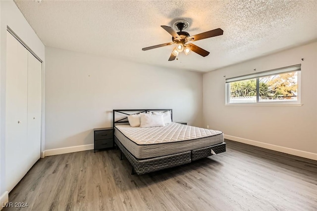 bedroom featuring ceiling fan, a closet, hardwood / wood-style floors, and a textured ceiling