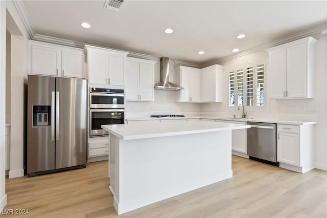 kitchen with a center island, white cabinets, wall chimney range hood, light hardwood / wood-style flooring, and stainless steel appliances