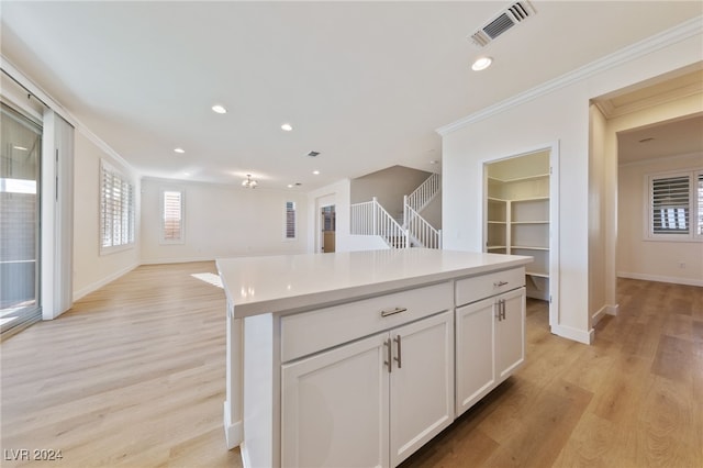 kitchen featuring white cabinets, crown molding, light hardwood / wood-style flooring, and a kitchen island