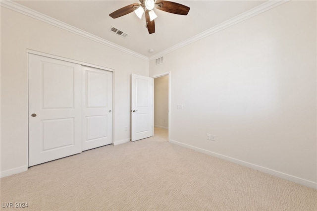 unfurnished bedroom featuring ceiling fan, a closet, light carpet, and ornamental molding