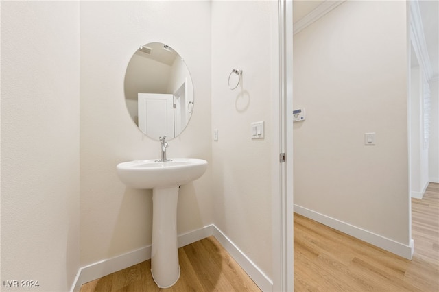 bathroom featuring hardwood / wood-style flooring and ornamental molding