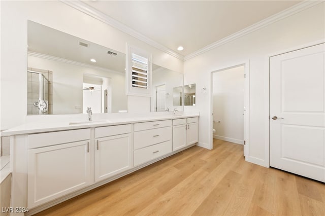 bathroom featuring ceiling fan, crown molding, wood-type flooring, a shower with door, and vanity